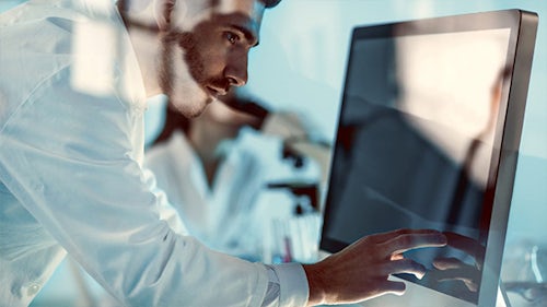 Muž pozorující obrazovku počítače a provádějící analýzu výkonnosti výrobku